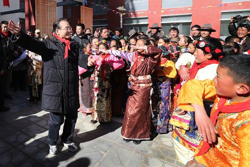 这是2012年12月31日,温家宝在玉树灾后重建的红旗小学与孩子们一起跳藏族舞蹈。 新华社记者姚大伟摄
