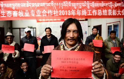 3月13日,入股牧民小娘吉合(前)在展示领取到的分红单。新华社记者 张宏祥 摄