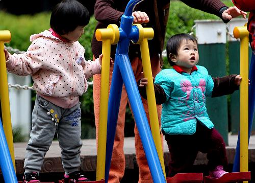 4月2日,一些小朋友在家长的看护下在上海街头公共绿地内玩耍。上海市卫生计生委4月1日发布的信息显示,上海市单独两孩政策自2014年3月1日实施以来,截至3月31日,全市共批准单独两孩再生育1730例,占同期再生育批准总量的60.8%,其中城市单独夫妻1444例,农村单独夫妻286例。新华社记者 陈飞 摄