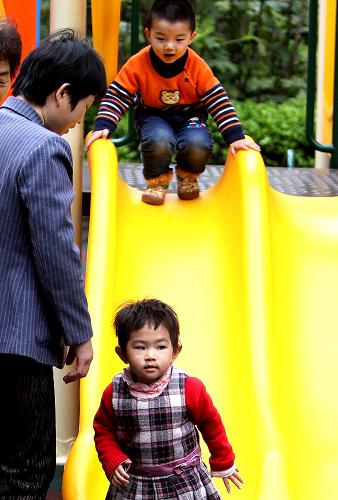 4月2日,一些小朋友在家长的看护下在上海街头公共绿地内玩耍。新华社记者 陈飞 摄