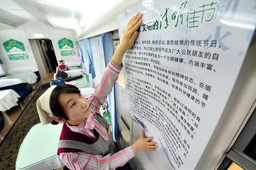 4月2日,兰州铁路局银川客运段一名餐车服务员在车厢里张贴文明祭扫的公益海报。新华社记者 彭昭之 摄
