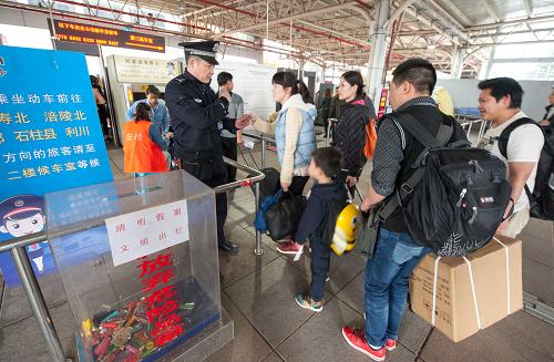 4月4日,一名铁路民警在重庆火车北站进站口提醒进站安检旅客将携带的易燃易爆物品放入危险品箱内。新华社记者 刘潺 摄