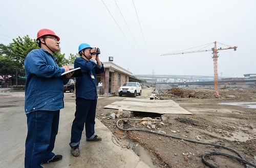 6月18日,电力工作人员在测量一处工地塔吊吊臂与周边输电线路的直线距离。从6月上旬开始,浙江省杭州市萧山区开展为期12天的输电安全联合整治行动,由萧山区供电公司、住建局安监站、公安等多部门联合发起,全面梳理高压输电线路周边的建设工地,对前期梳理发现的共18个施工隐患现场进行集中性整治,涉及110千伏线路13条,35千伏线路5条,力争全面消除供电线路周边间距过近带来的安全隐患。新华社记者徐昱摄